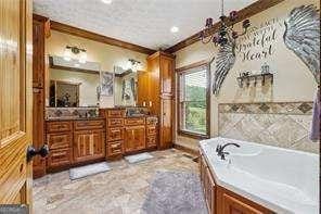 bathroom with a bathing tub, vanity, and ornamental molding