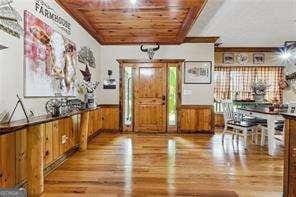 entrance foyer with wooden walls, wooden ceiling, and light hardwood / wood-style flooring