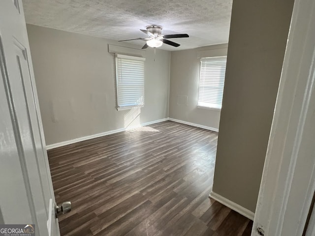 empty room with dark wood-style floors, ceiling fan, a textured ceiling, and baseboards