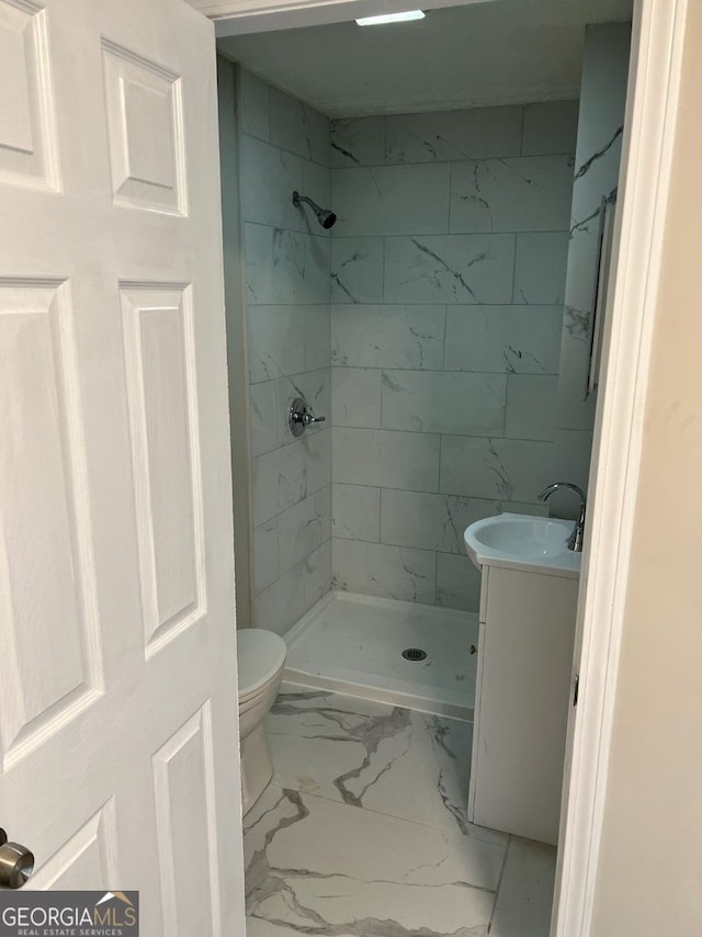 bathroom featuring marble finish floor, a shower stall, toilet, and vanity