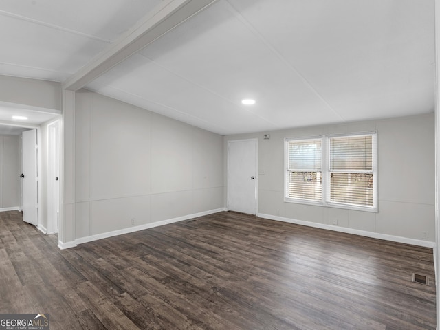 empty room featuring dark wood-type flooring and beamed ceiling