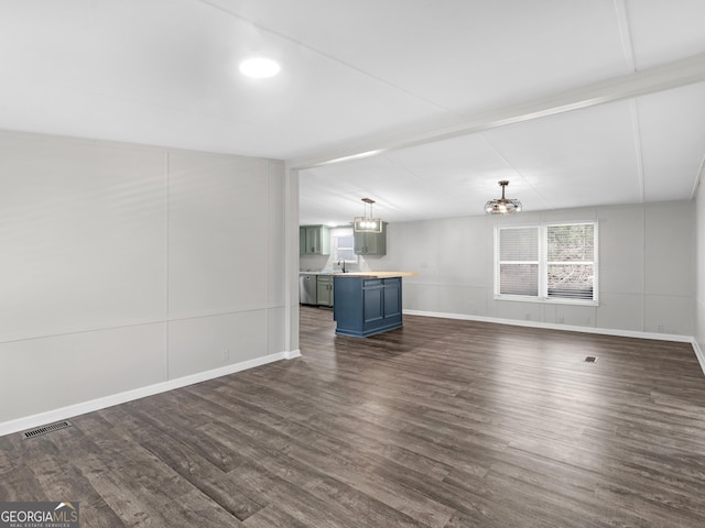 unfurnished living room featuring an inviting chandelier, dark hardwood / wood-style floors, sink, and vaulted ceiling with beams