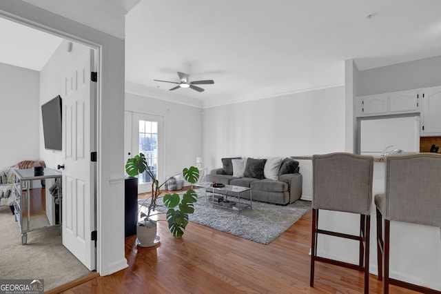 living room with crown molding, ceiling fan, and light hardwood / wood-style flooring