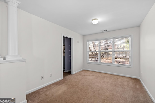 spare room featuring light carpet and ornate columns