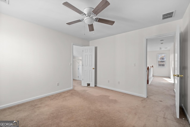 unfurnished bedroom with a spacious closet, a closet, light carpet, and ceiling fan