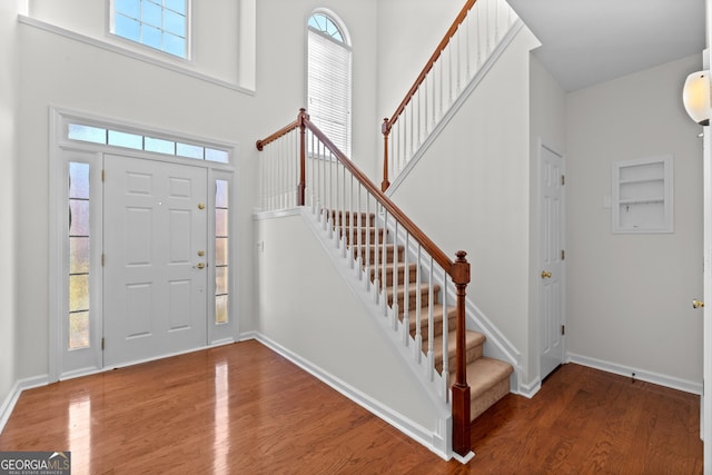 foyer entrance with hardwood / wood-style flooring and a towering ceiling