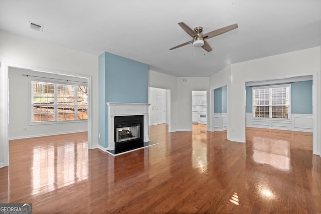 unfurnished living room with a multi sided fireplace, hardwood / wood-style flooring, and ceiling fan