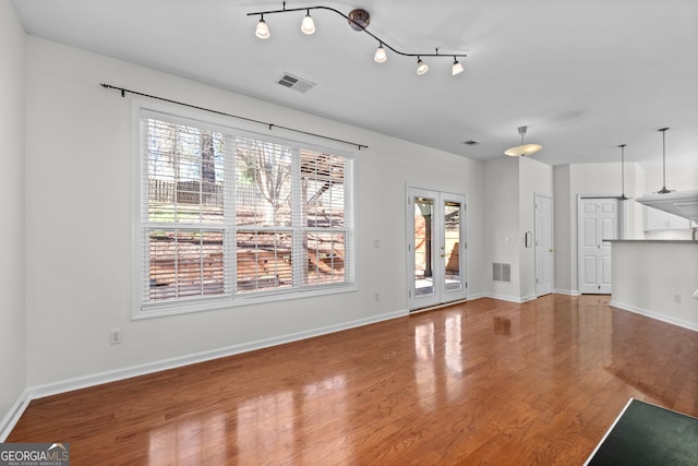 unfurnished living room featuring hardwood / wood-style flooring and french doors