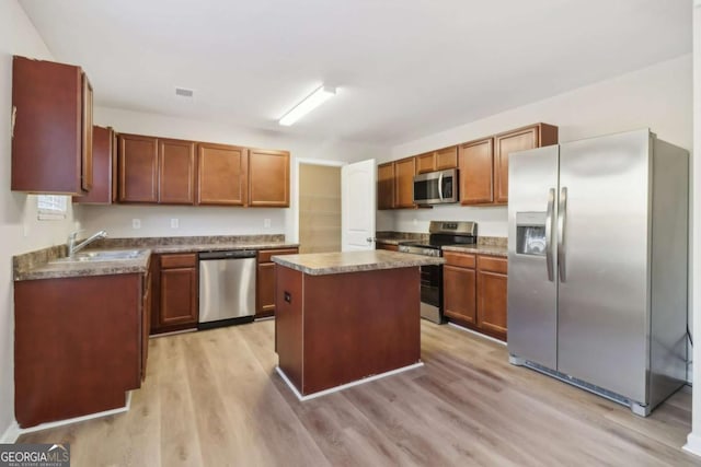 kitchen with sink, a center island, stainless steel appliances, and light wood-type flooring