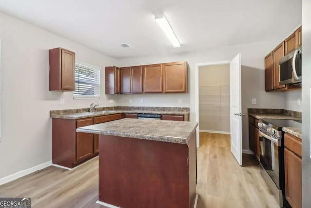 kitchen with sink, stainless steel appliances, a kitchen island, and light wood-type flooring