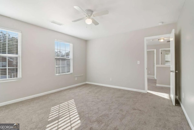 unfurnished bedroom with ceiling fan, light carpet, and multiple windows