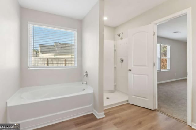 bathroom featuring wood-type flooring and shower with separate bathtub