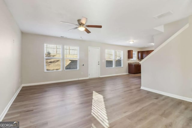 unfurnished living room featuring ceiling fan and hardwood / wood-style floors