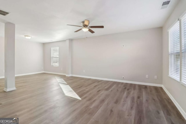 empty room featuring ceiling fan, a wealth of natural light, and dark hardwood / wood-style flooring