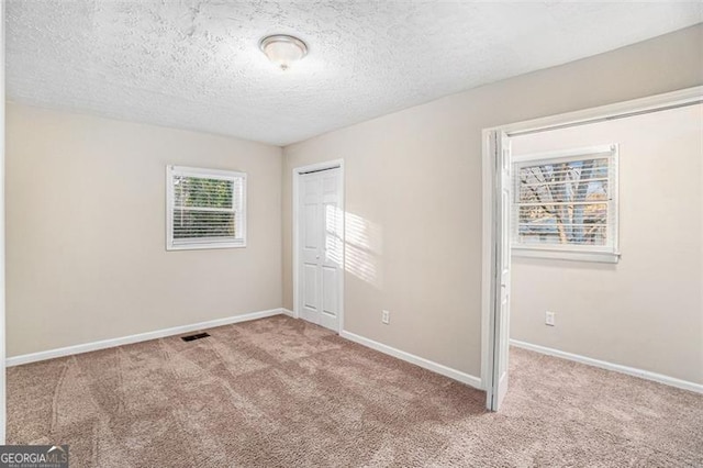 carpeted empty room featuring a textured ceiling