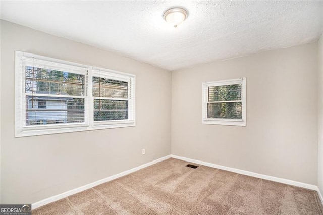 carpeted empty room featuring a textured ceiling