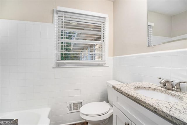 bathroom with tile walls, toilet, vanity, and a bathing tub