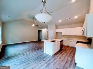 kitchen featuring appliances with stainless steel finishes, white cabinetry, lofted ceiling, hardwood / wood-style flooring, and a kitchen island with sink