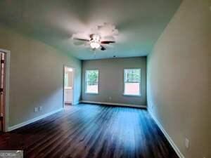 spare room featuring dark wood-type flooring and ceiling fan