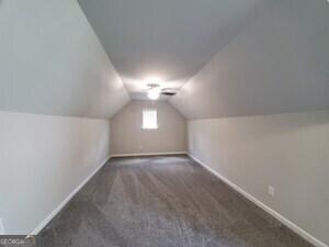 bonus room with vaulted ceiling and dark carpet