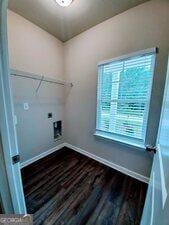 washroom featuring dark wood-type flooring, hookup for an electric dryer, and a healthy amount of sunlight