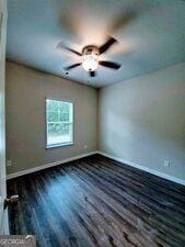 spare room featuring dark wood-type flooring and ceiling fan