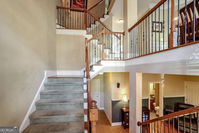 stairs with a towering ceiling and hardwood / wood-style floors