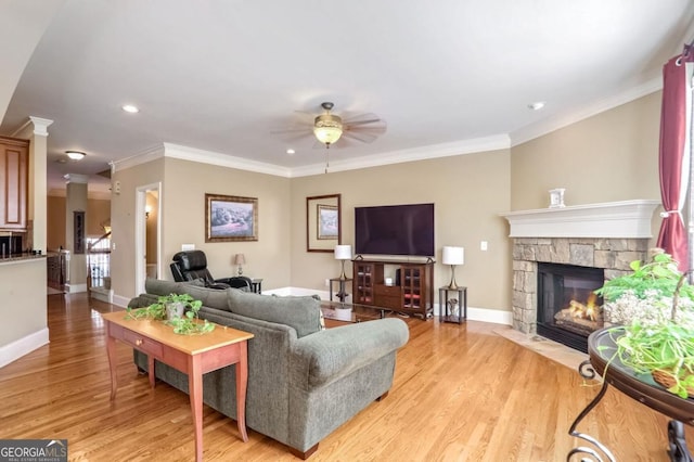 living room featuring ceiling fan, light hardwood / wood-style flooring, crown molding, and a fireplace