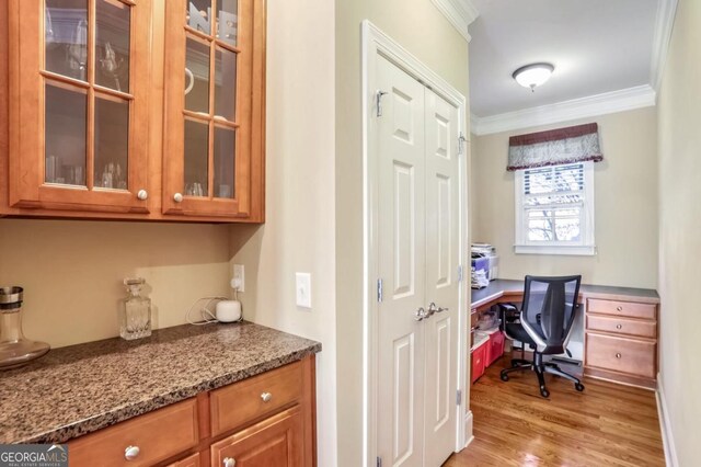 kitchen featuring crown molding, appliances with stainless steel finishes, light wood-type flooring, tasteful backsplash, and light stone counters