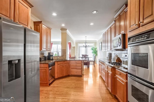 kitchen featuring tasteful backsplash, hanging light fixtures, sink, ornamental molding, and stainless steel appliances