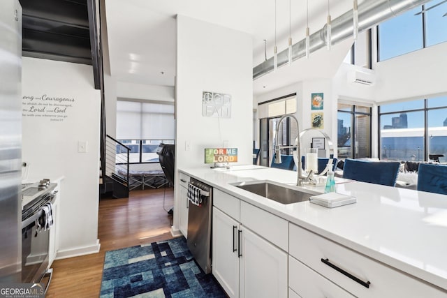 kitchen with dark hardwood / wood-style flooring, sink, appliances with stainless steel finishes, white cabinetry, and a towering ceiling