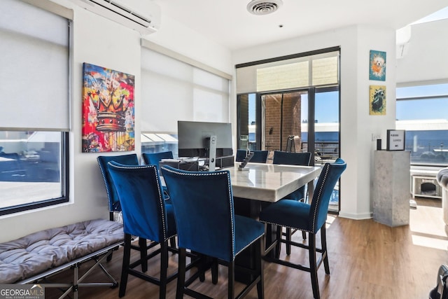 dining area with hardwood / wood-style floors and a wall unit AC