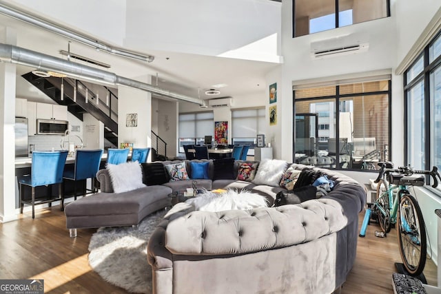 living room featuring hardwood / wood-style flooring, an AC wall unit, and plenty of natural light