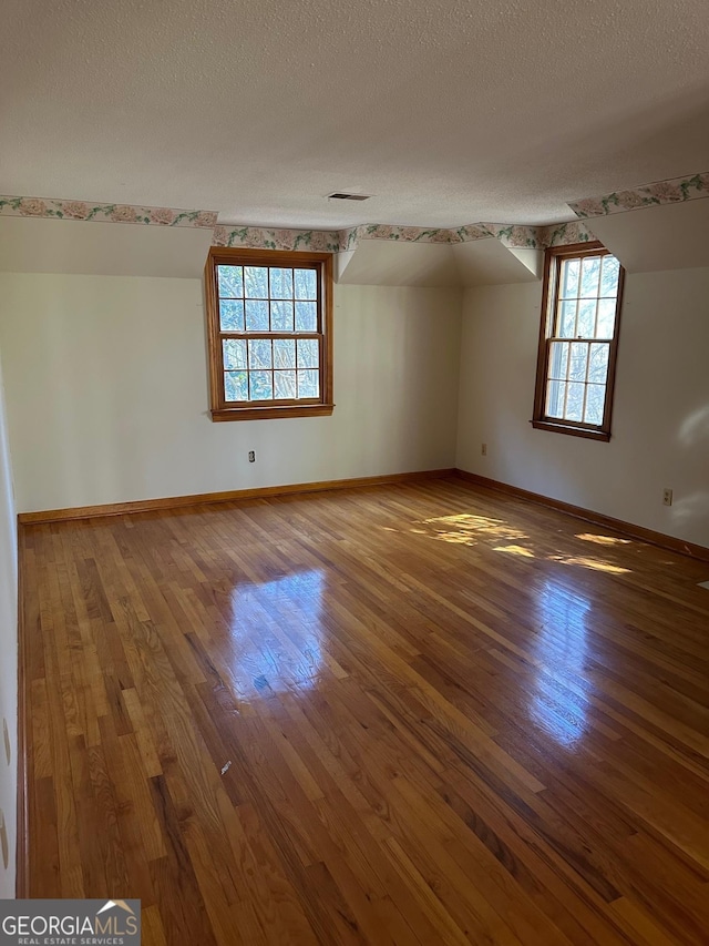 spare room featuring hardwood / wood-style flooring and a textured ceiling