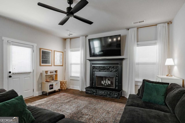 living room with wood-type flooring, a wealth of natural light, a high end fireplace, and ceiling fan