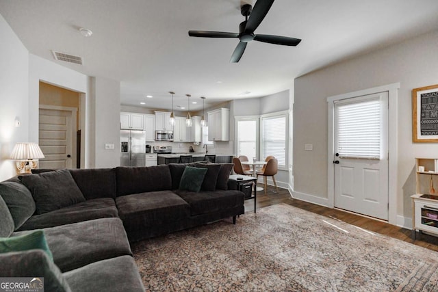 living room featuring ceiling fan, dark wood-type flooring, and sink