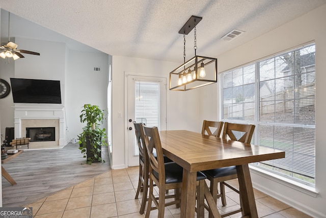 tiled dining area with a textured ceiling and ceiling fan