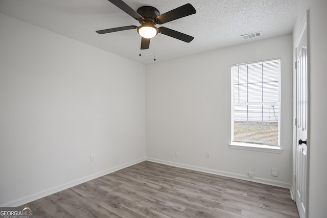 unfurnished room with ceiling fan, light hardwood / wood-style flooring, and a textured ceiling