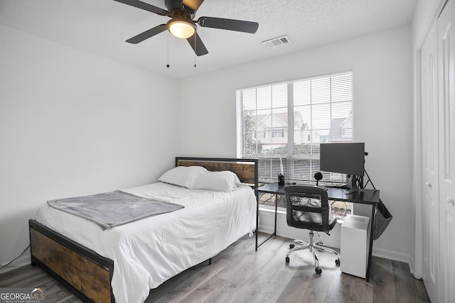 bedroom featuring hardwood / wood-style flooring, ceiling fan, a closet, and a textured ceiling