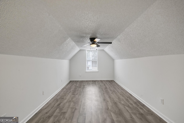 bonus room featuring ceiling fan, lofted ceiling, hardwood / wood-style floors, and a textured ceiling