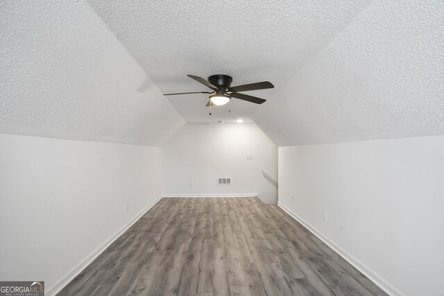 bonus room featuring ceiling fan, lofted ceiling, hardwood / wood-style floors, and a textured ceiling