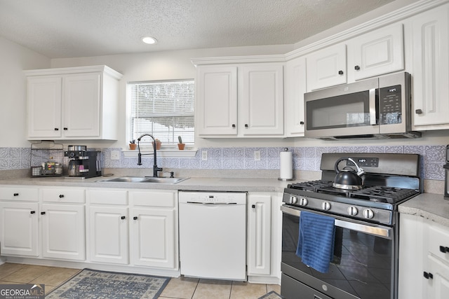 kitchen featuring light tile patterned flooring, sink, a textured ceiling, stainless steel appliances, and white cabinets