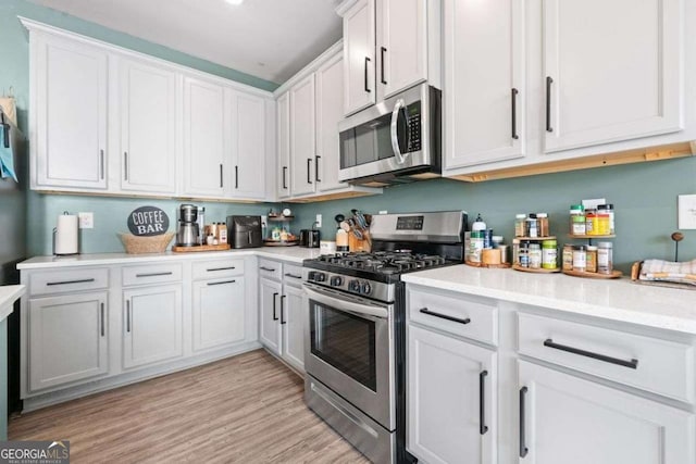 kitchen with white cabinets, light hardwood / wood-style floors, appliances with stainless steel finishes, and sink