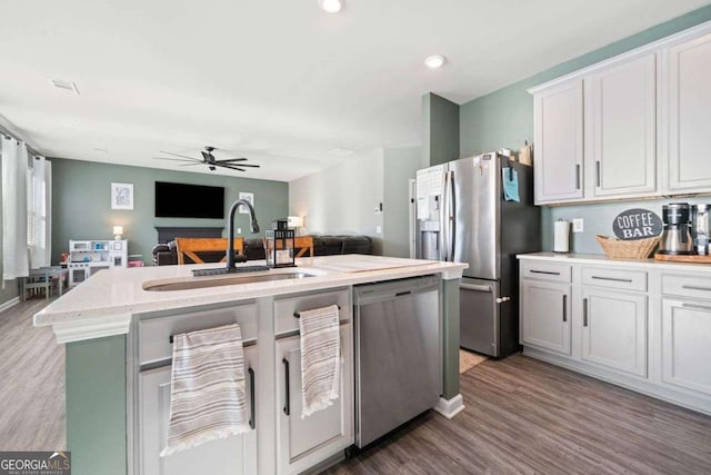 kitchen featuring white cabinets, stainless steel appliances, light stone counters, and light hardwood / wood-style floors