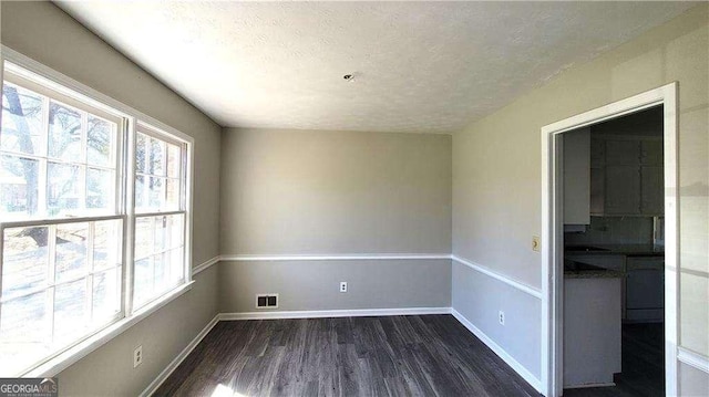 empty room featuring a textured ceiling and dark hardwood / wood-style flooring