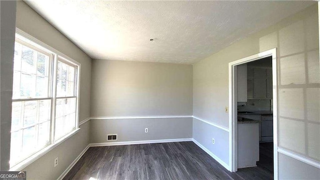 unfurnished room with a textured ceiling and dark hardwood / wood-style flooring