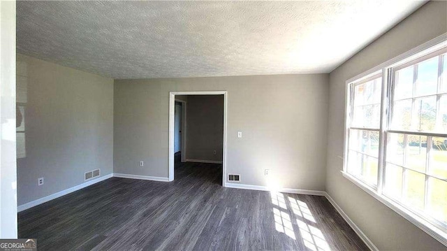 spare room featuring a textured ceiling, dark hardwood / wood-style floors, and a wealth of natural light