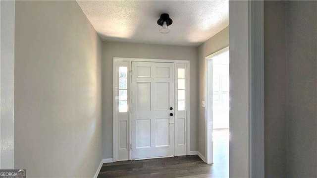 entrance foyer with dark wood-type flooring, a textured ceiling, and a healthy amount of sunlight