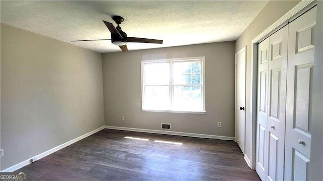 unfurnished bedroom with a textured ceiling, a closet, ceiling fan, and dark hardwood / wood-style flooring