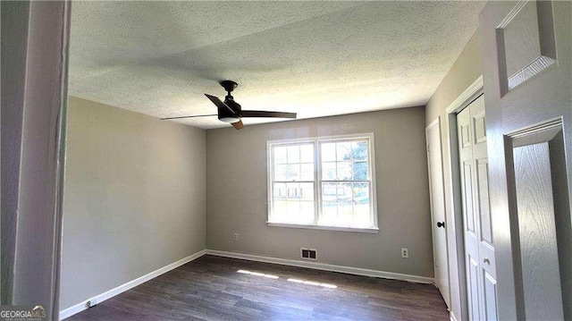 unfurnished room with ceiling fan, dark hardwood / wood-style floors, and a textured ceiling